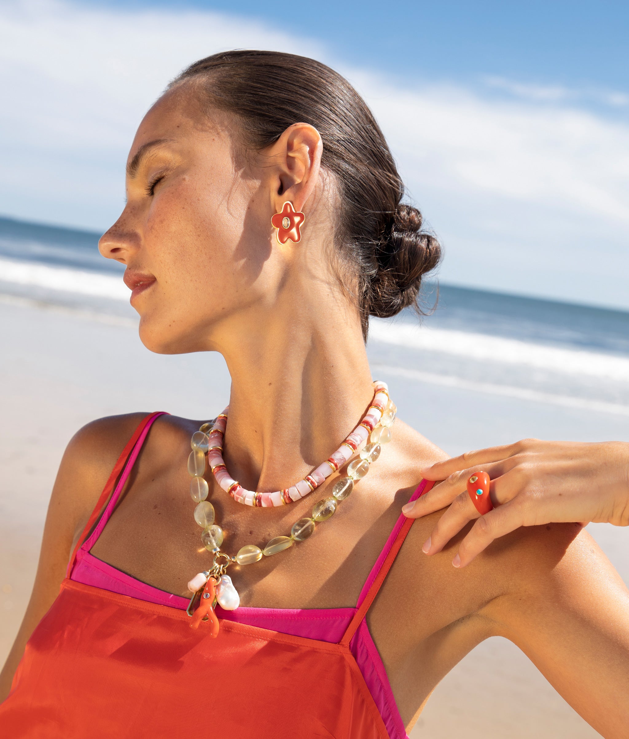 Model wearing the Beaded Reef Necklace paired with the Rosado Necklace and red chunky star-shaped earrings.