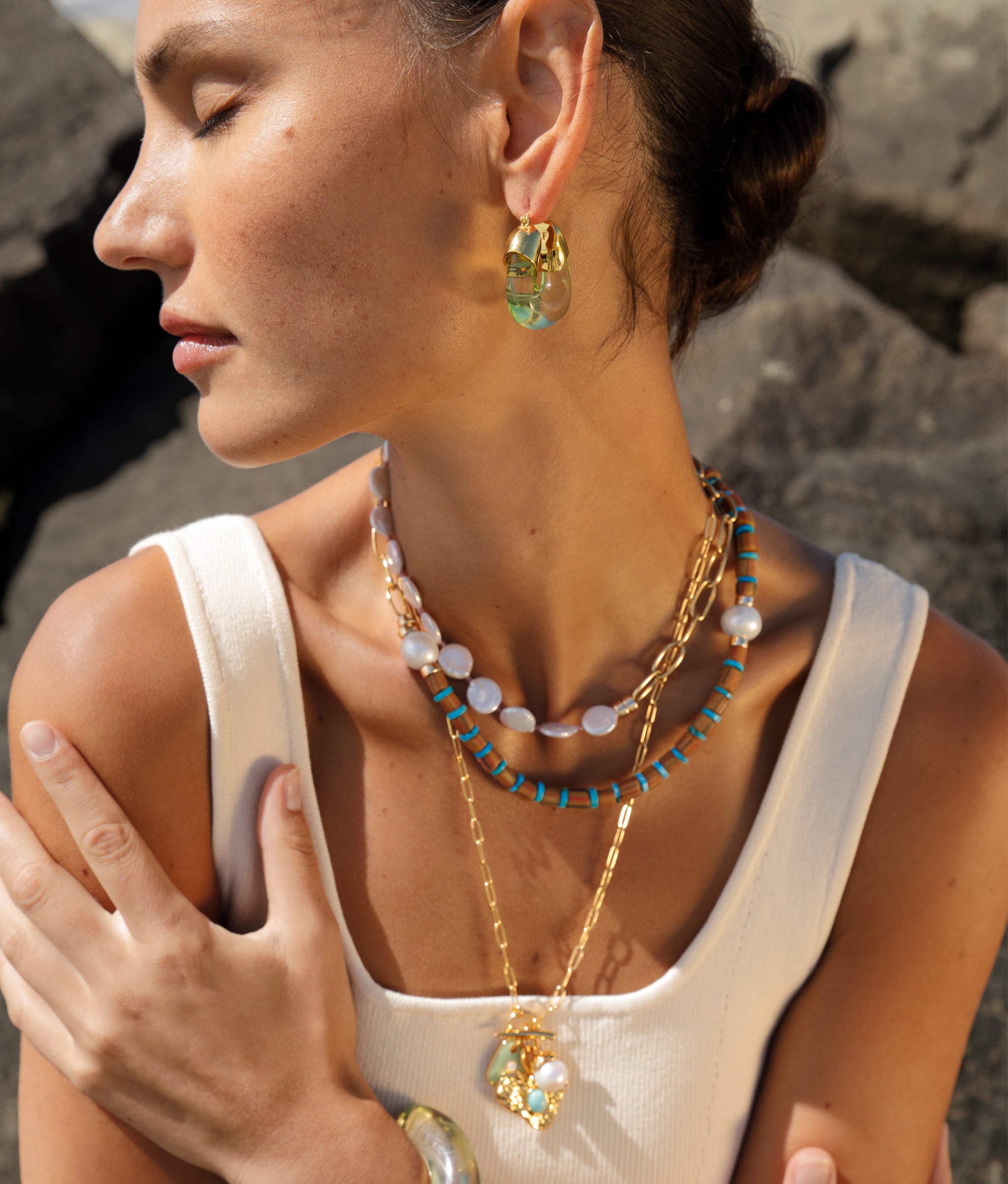 Model wearing Porto Covo Necklace in Azul with Organic Hoops in Lime, Treasure Heart Pendent and Mint Grotto Necklaces.
