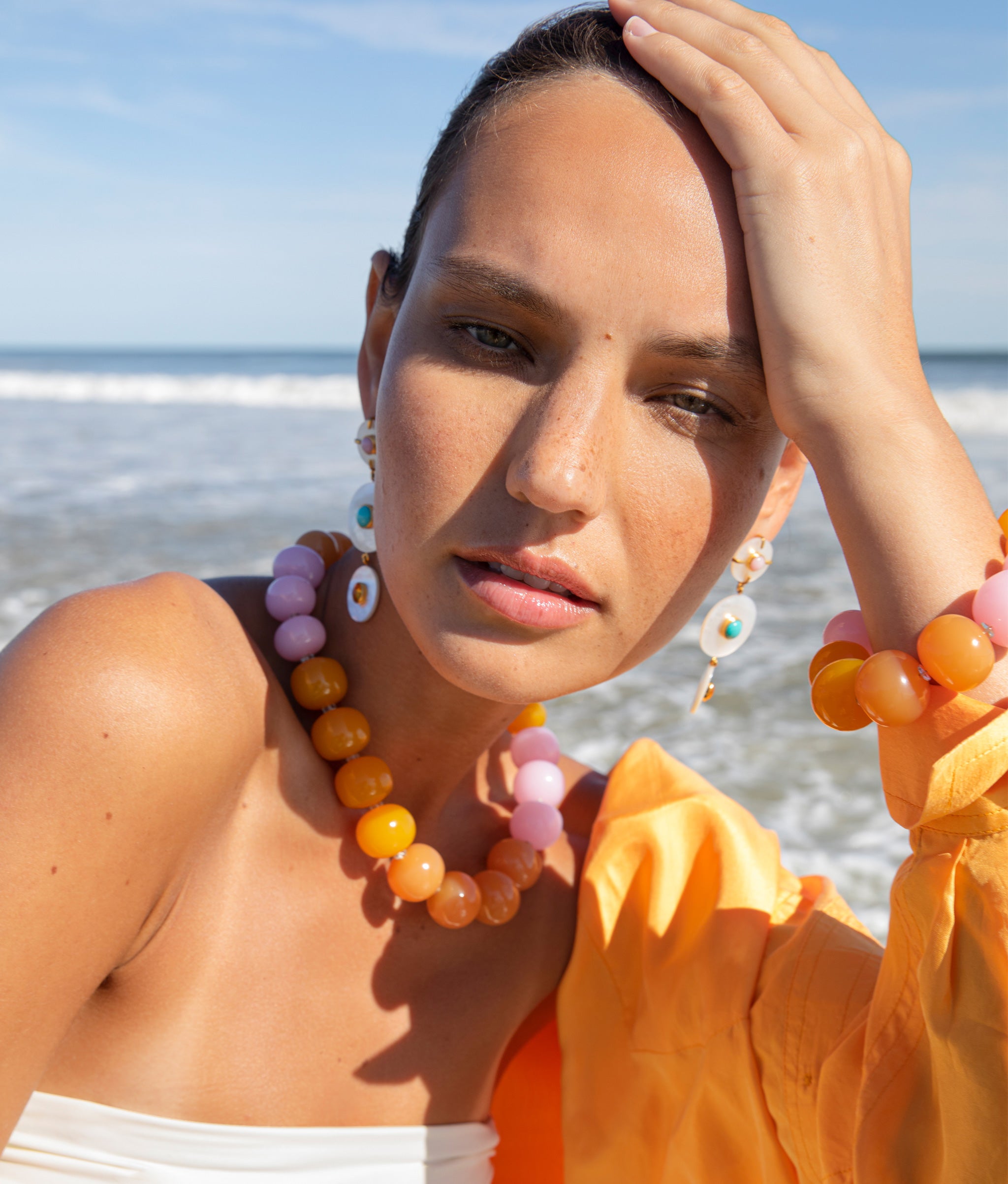 Close up of Model at the beach wearing Olympia Bracelet and Collar set paired with Tropic Pearl Earrings.