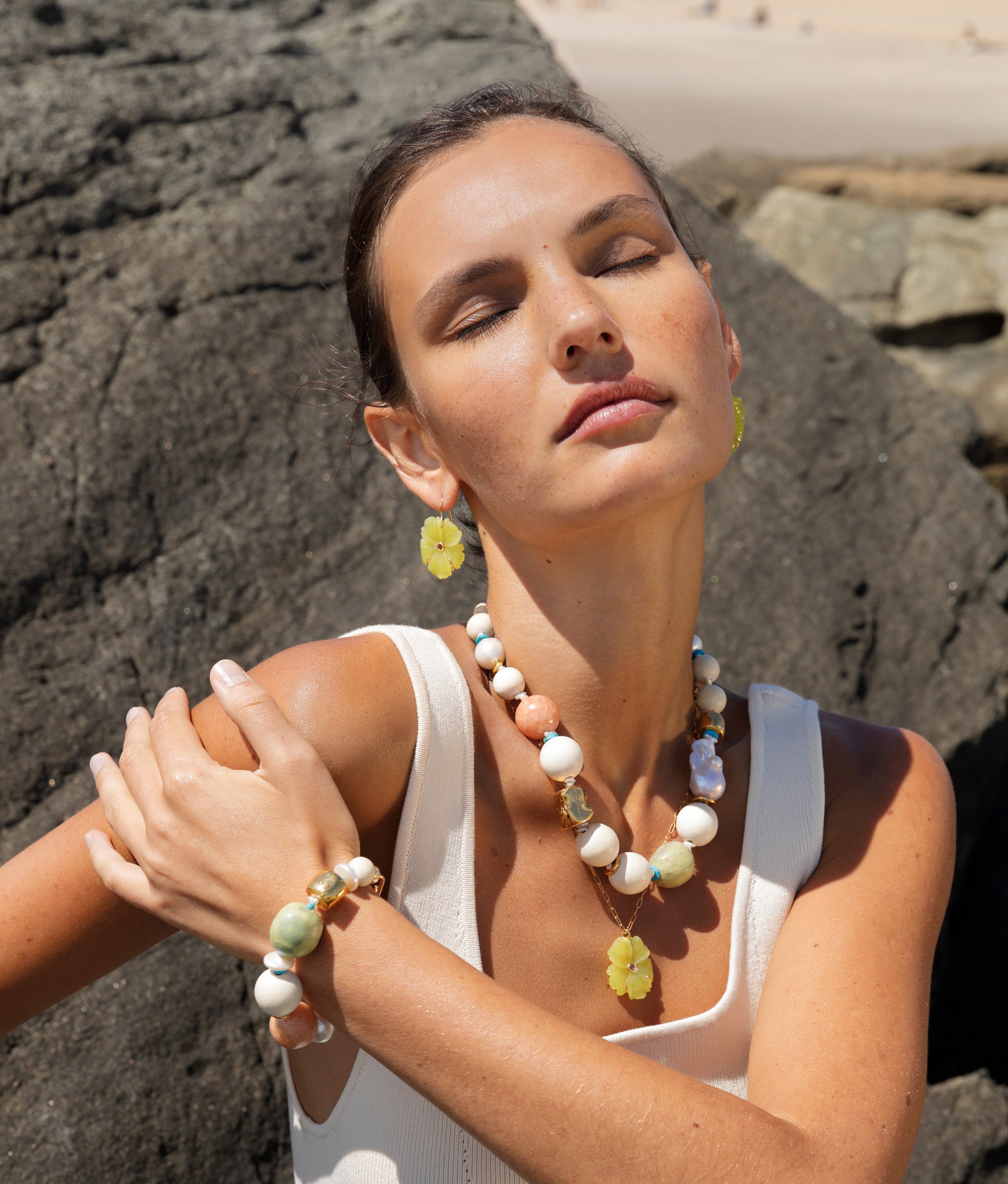 Another angle of model wearing Andros Bracelet and Necklace, paired with yellow-green floral necklace and earrings.