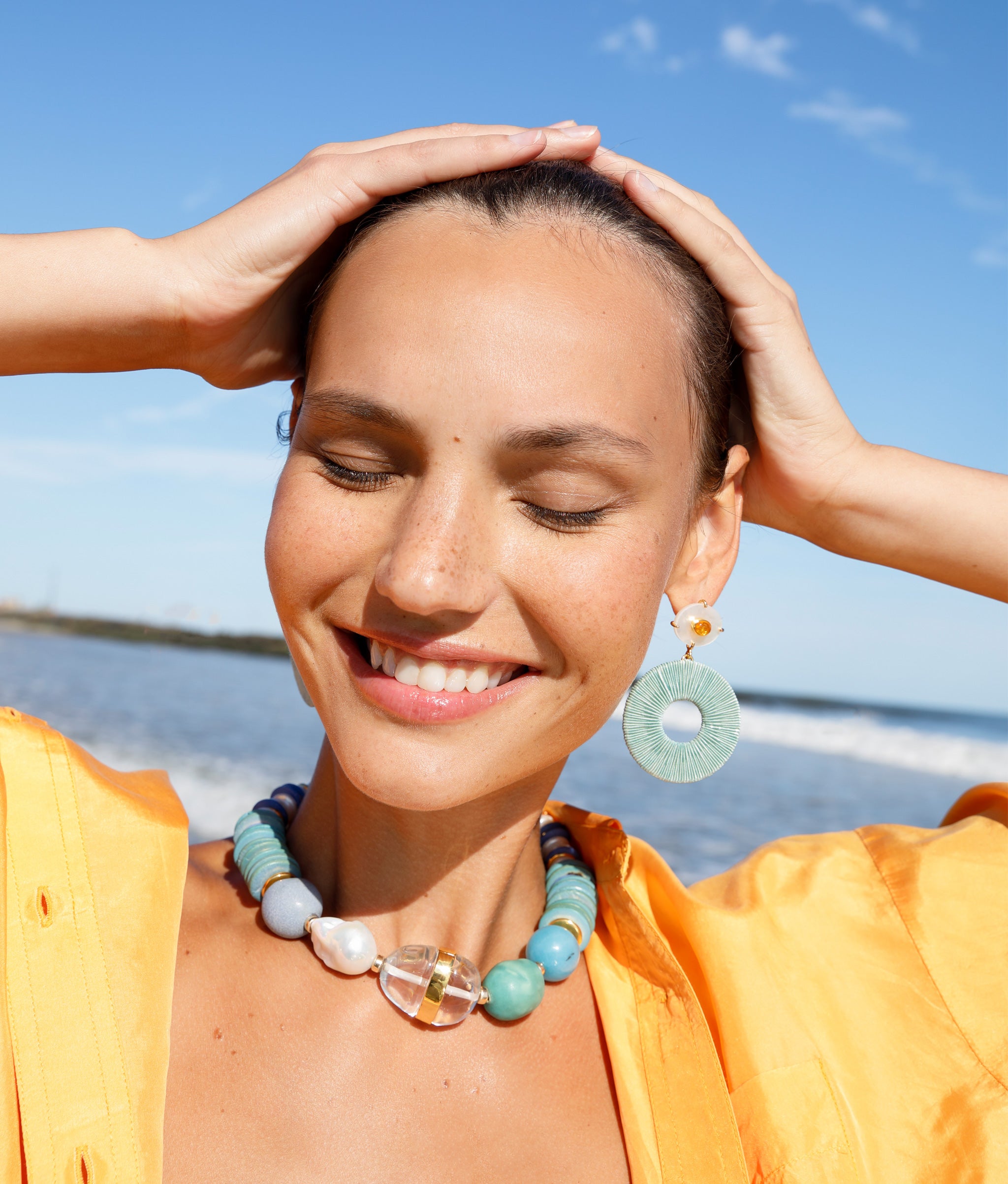 Close-up of model at the beach wearing Neptune Collar paired with Domingo Earrings.