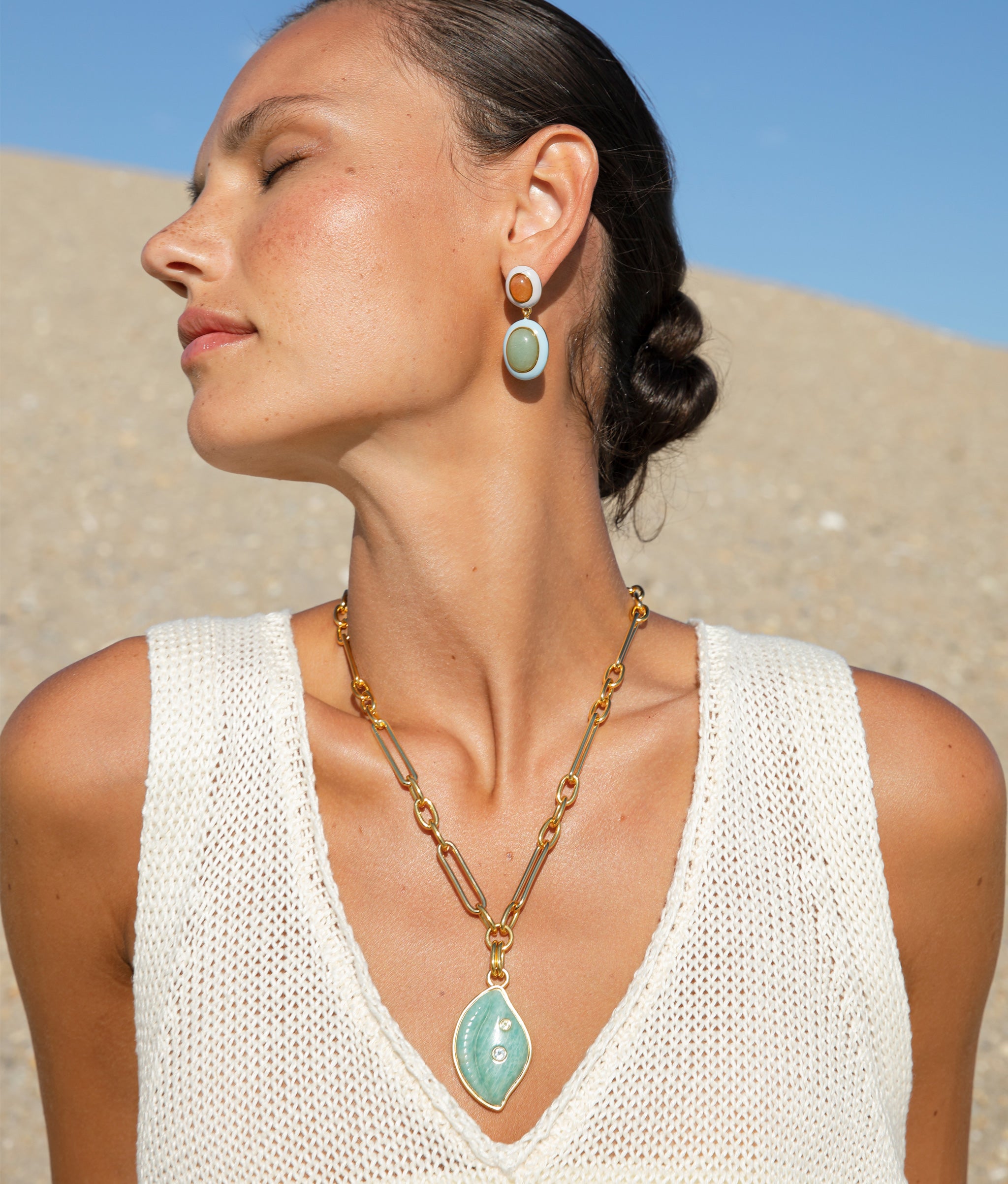 Close-up of model wearing Cowrie Shell Necklace in Amazonite paired with Cabana Necklace in Wave and Papaya Earrings.