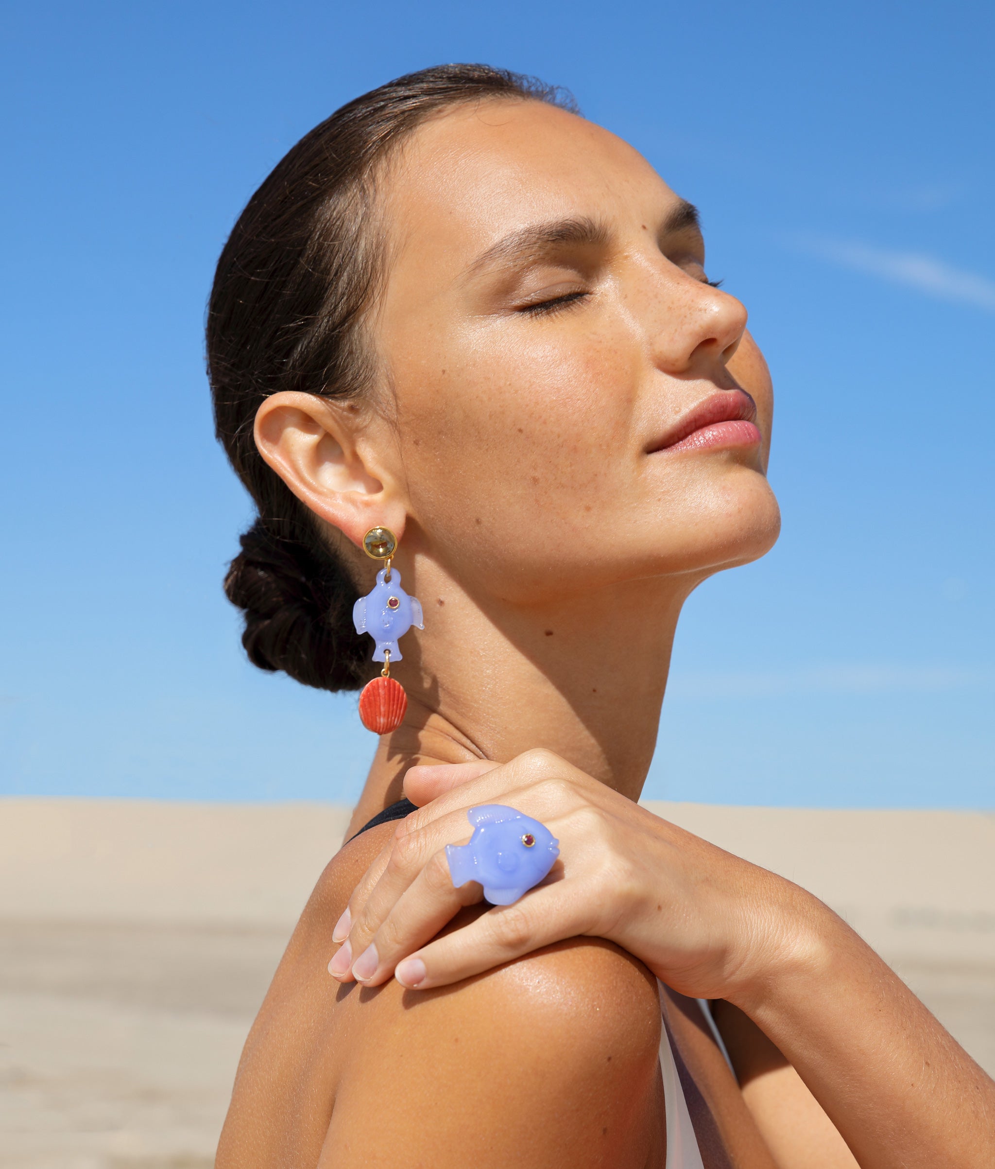 Close-up of model on the beach wearing the Pescado Ring with the Pescado Earrings.