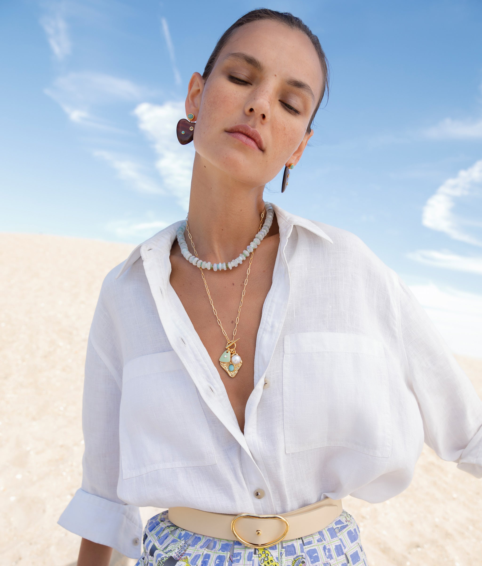 Model at the beach wearing the Wide Georgia Belt in Butter paired with earth-toned earrings and necklaces.