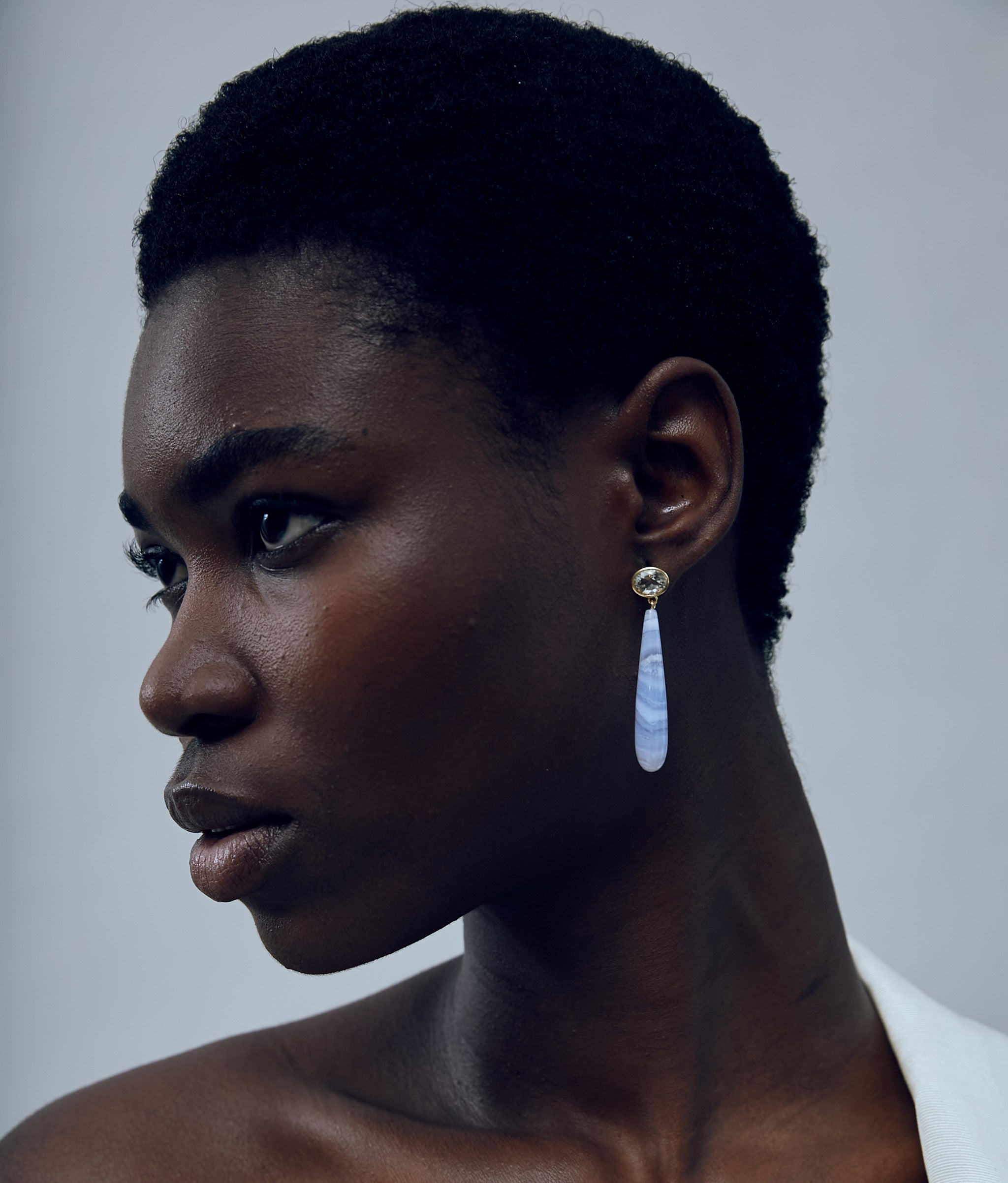 Another angle of model on grey background with 14k Gold Drop Earrings in Green Amethyst & Blue Lace Agate. 