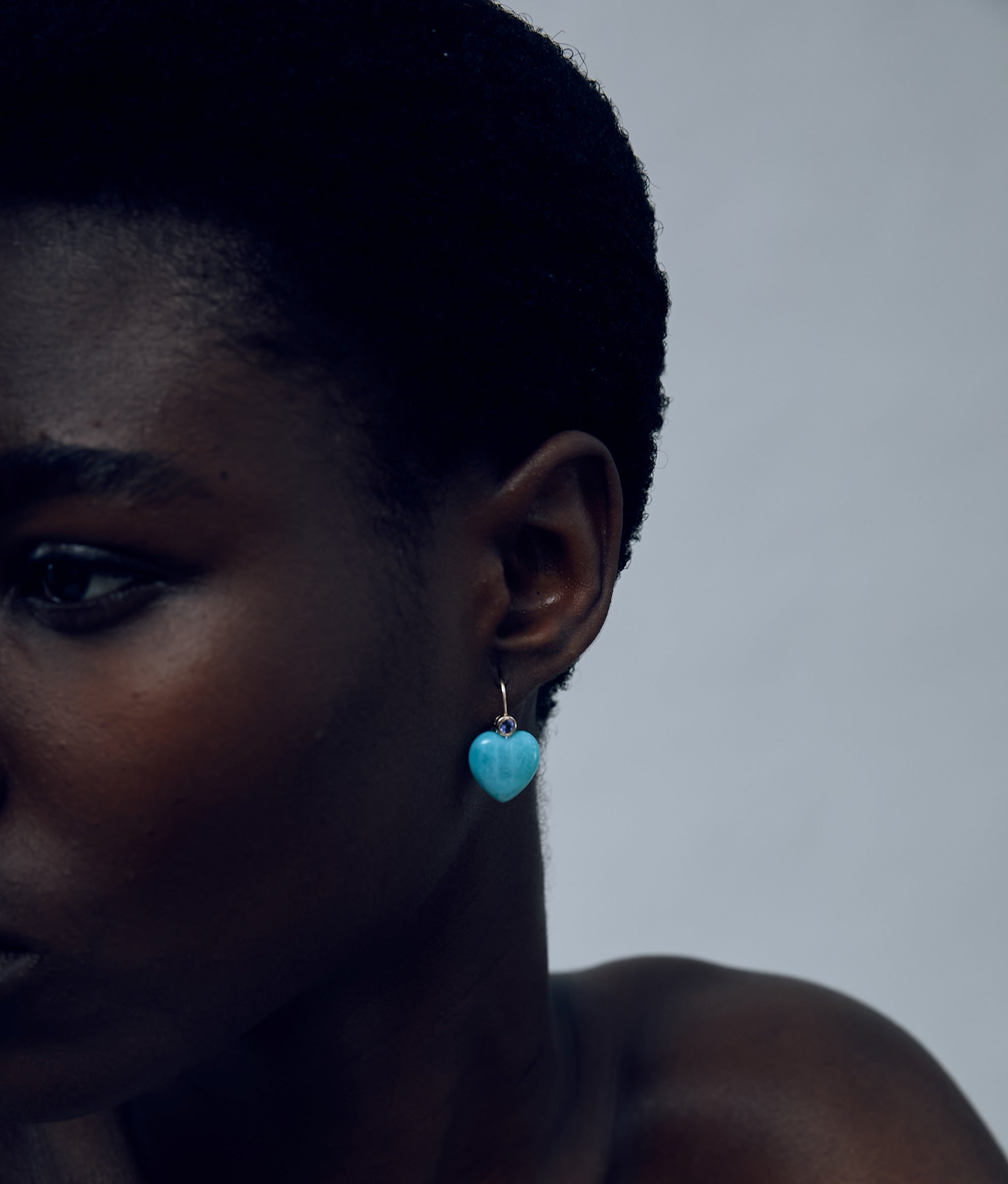 Close-up of model on grey background wearing the 14k Gold Amor Earrings in Tanzanite & Amazonite. 
