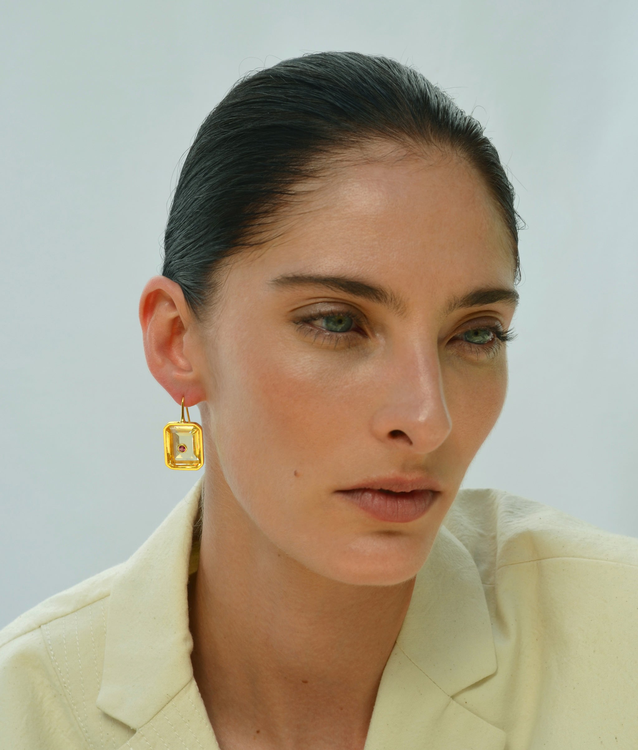 Model on light blue backdrop wears yellow top with Tile Earrings in Citrine.