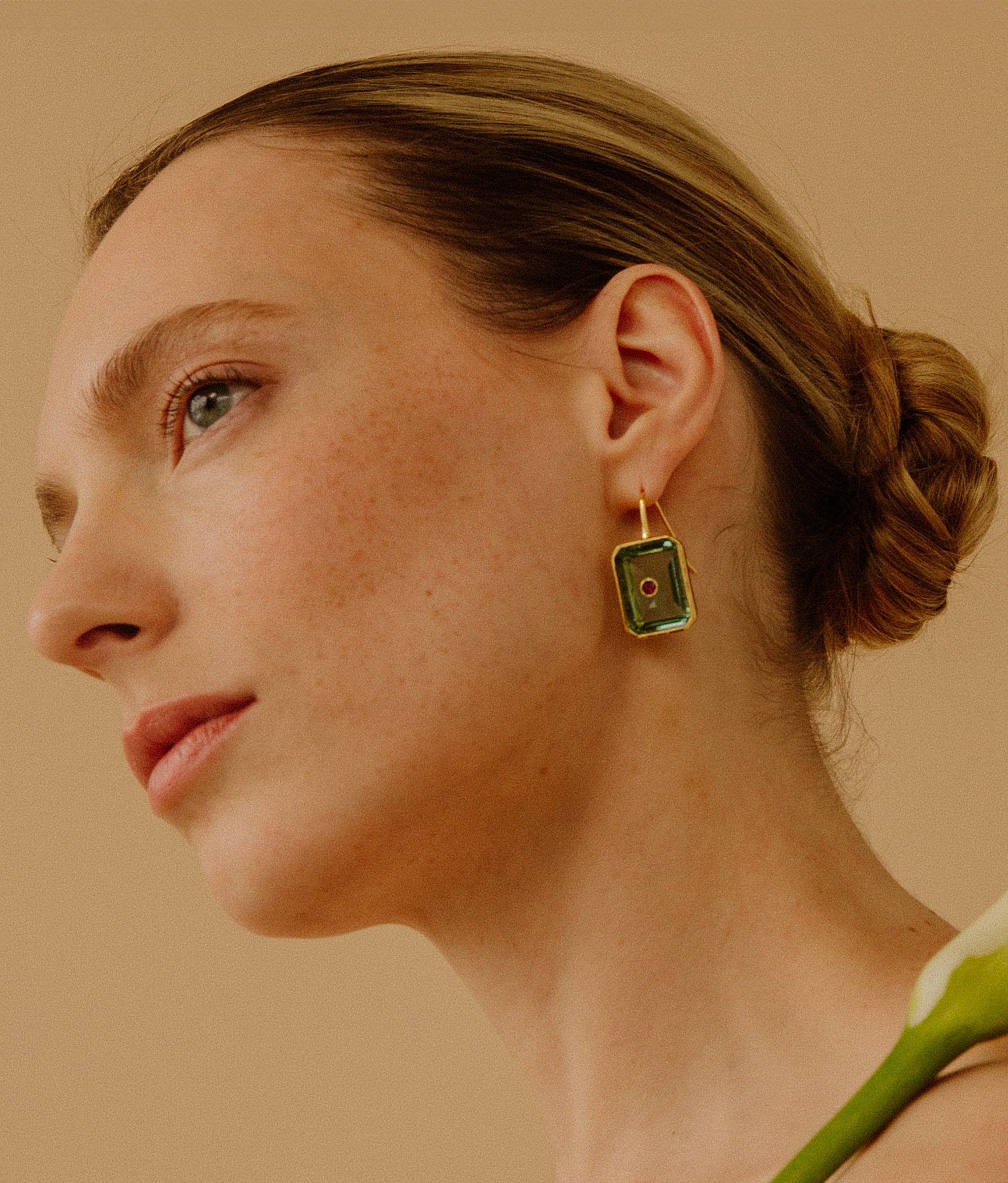 Model on tan background wearing the Tile Earrings in Aqua.