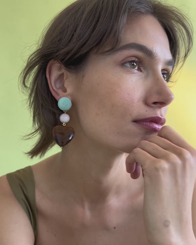 Model in close-up poses on green backdrop and wears the Long Weekend Earrings.