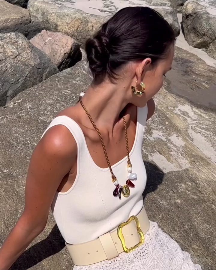 Video of model on rock background wearing Olive Branch Necklace paired with Saucer Hoops in Dotted Stone.