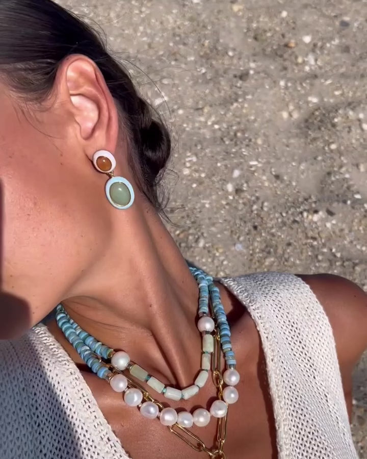 Video of model wearing Cowrie Shell Necklace in Amazonite paired with Cabana Necklace in Wave and Papaya Earrings.