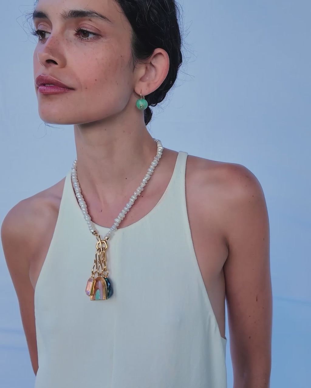 Video of model wearing white tank top and Mood Necklace in Pearl with assorted charms and Comet Earrings.
