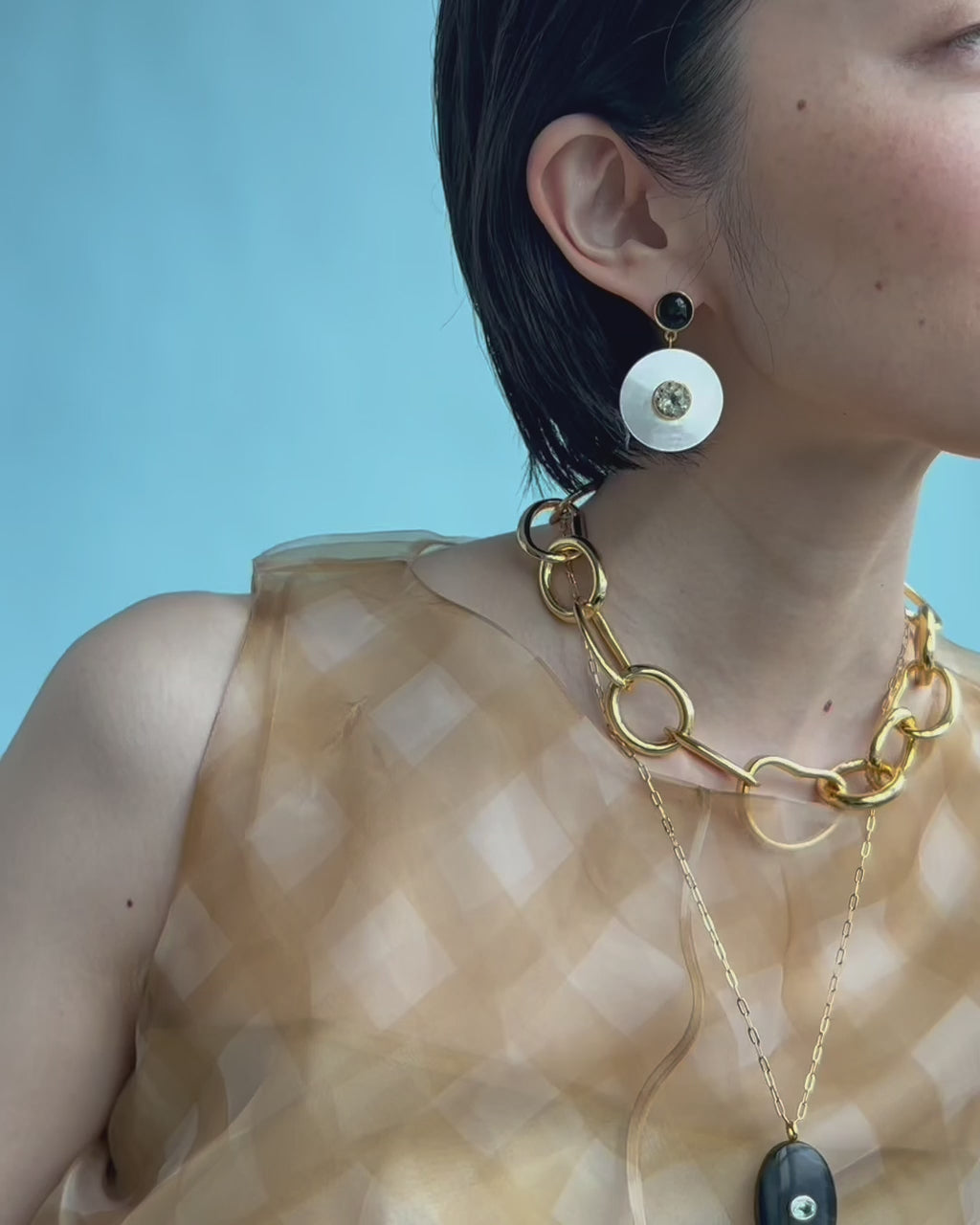 Video shows model wearing Taj Disc Earrings In Mother-Of-Pearl and Porto Chain