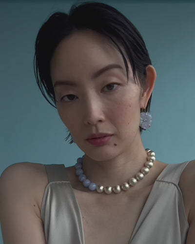 Close-up video of model on an aqua backdrop wearing New Bloom Earrings and Silver Sky Collar