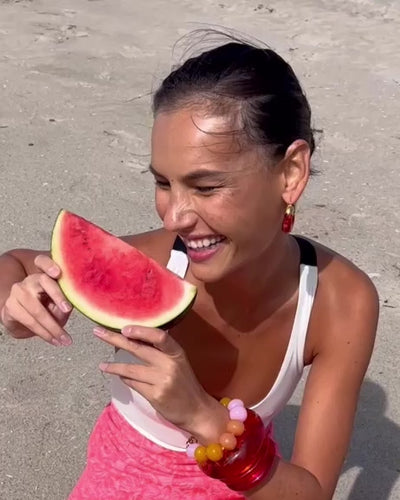 Video of model with watermelon wearing Olympia Bracelet with Organic Hoops, Arc and Ridge Cuff in Persimmon and Magenta.