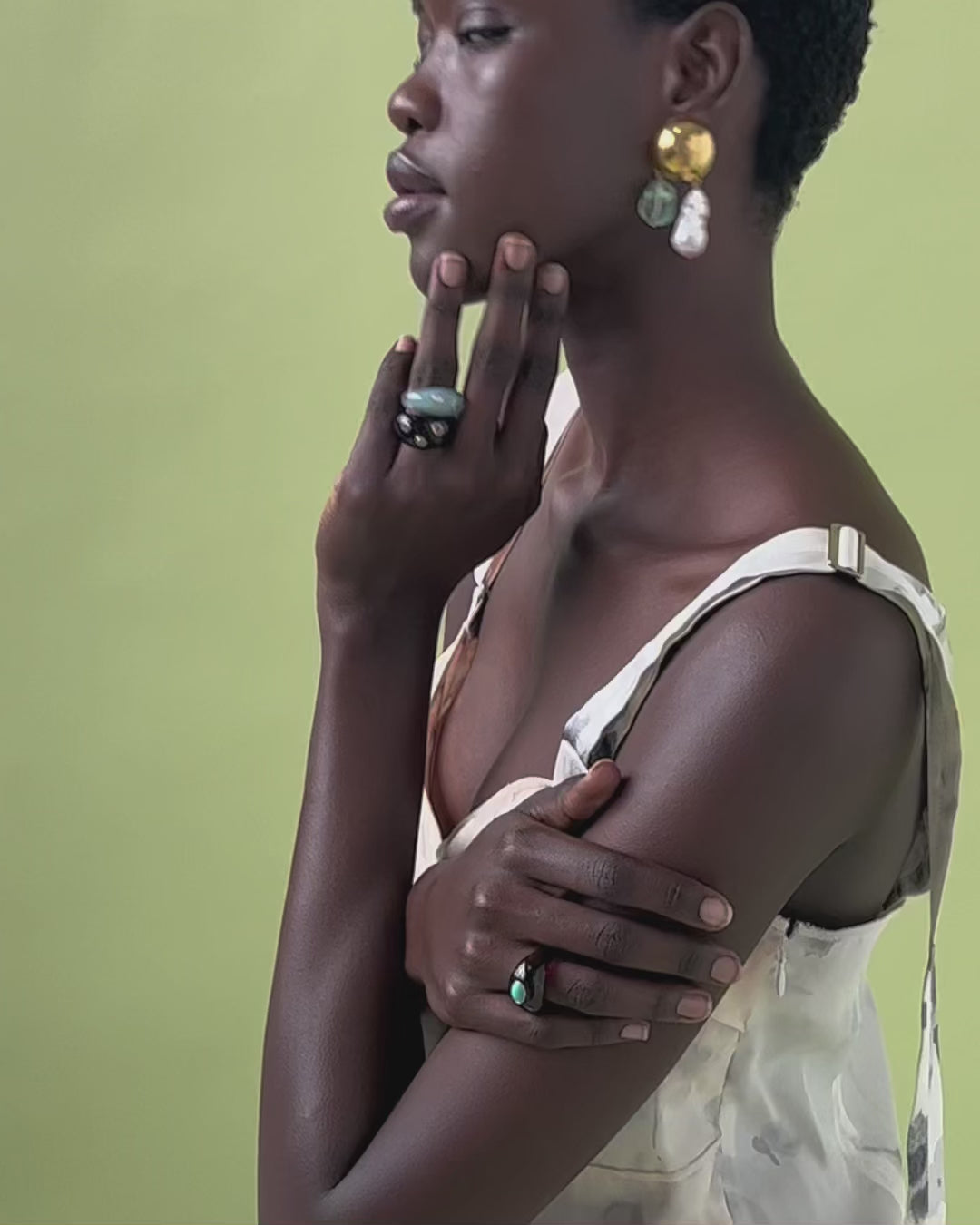 Video of model on green backdrop in floral dress, Cascada Earrings, and assorted Monument Rings.