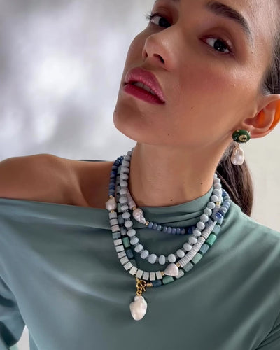 Video shows a close-up of model wearing Cabana Necklace in Azure Sky layered with other Lizzie Fortunato's pieces.