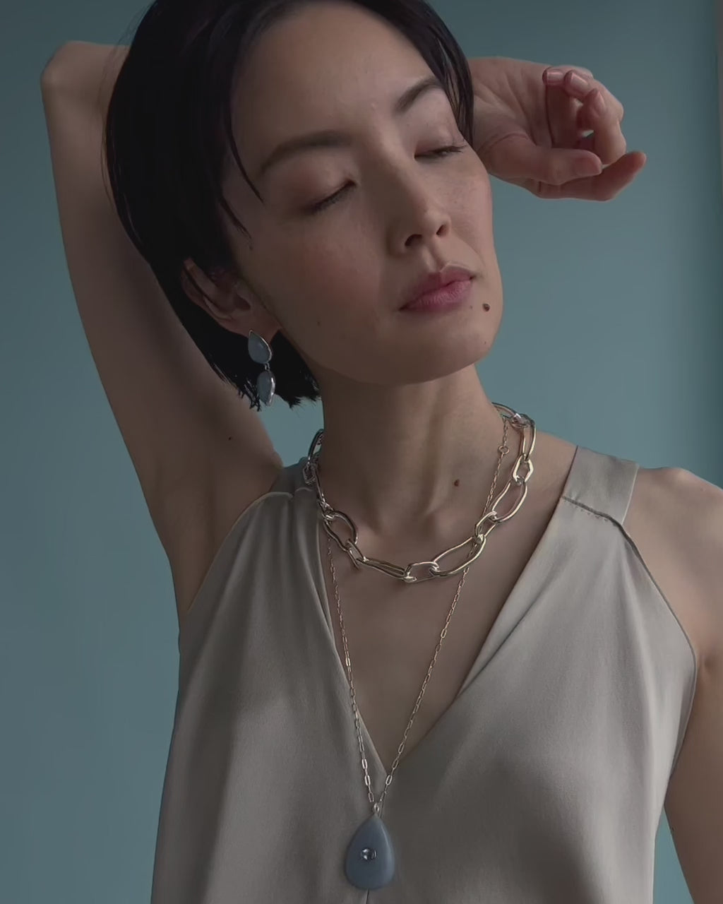 Video shows a close-up of model wearing Collage Necklace in Silver with Electra Earrings in Angelite.