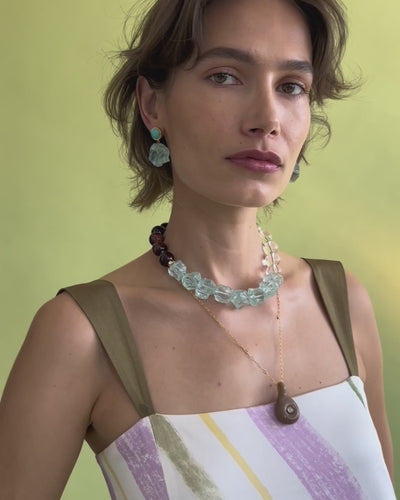 Video of model posing on green backdrop in dress with Glacier Bay Earrings, Necklace and Muse Pendant in Sandstone.