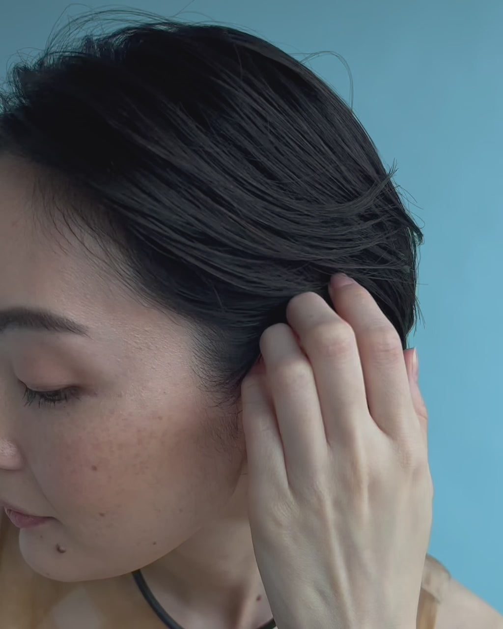 Video shows a close-up of model wearing Esme Collar and Mazu Studs earrings in a blue backdrop. 