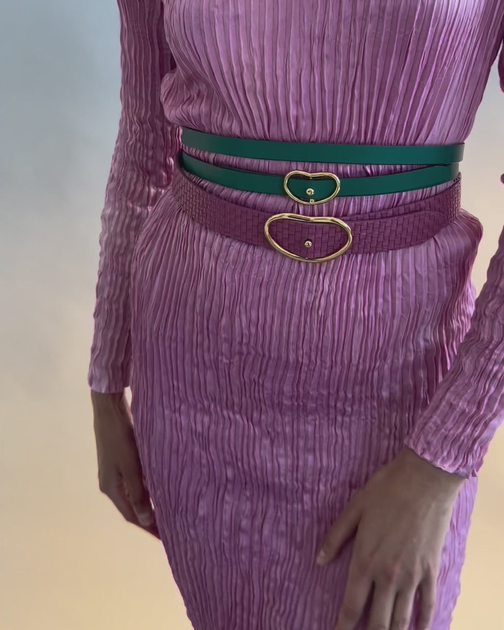 Close-up video of model's torso in pink pleated dress with Wide Georgia Belt in Flamingo Weave, and green leather belt.