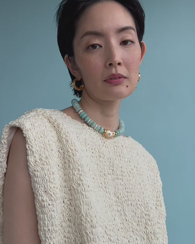 Video shows a close-up of model wearing Goddess Collar In Pearl Lagoon styled with Onda Hoops In Gold