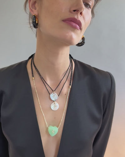Video of model on grey backdrop in black blazer with Gemini Necklace, two Meret Necklaces, and Organic Hoops.