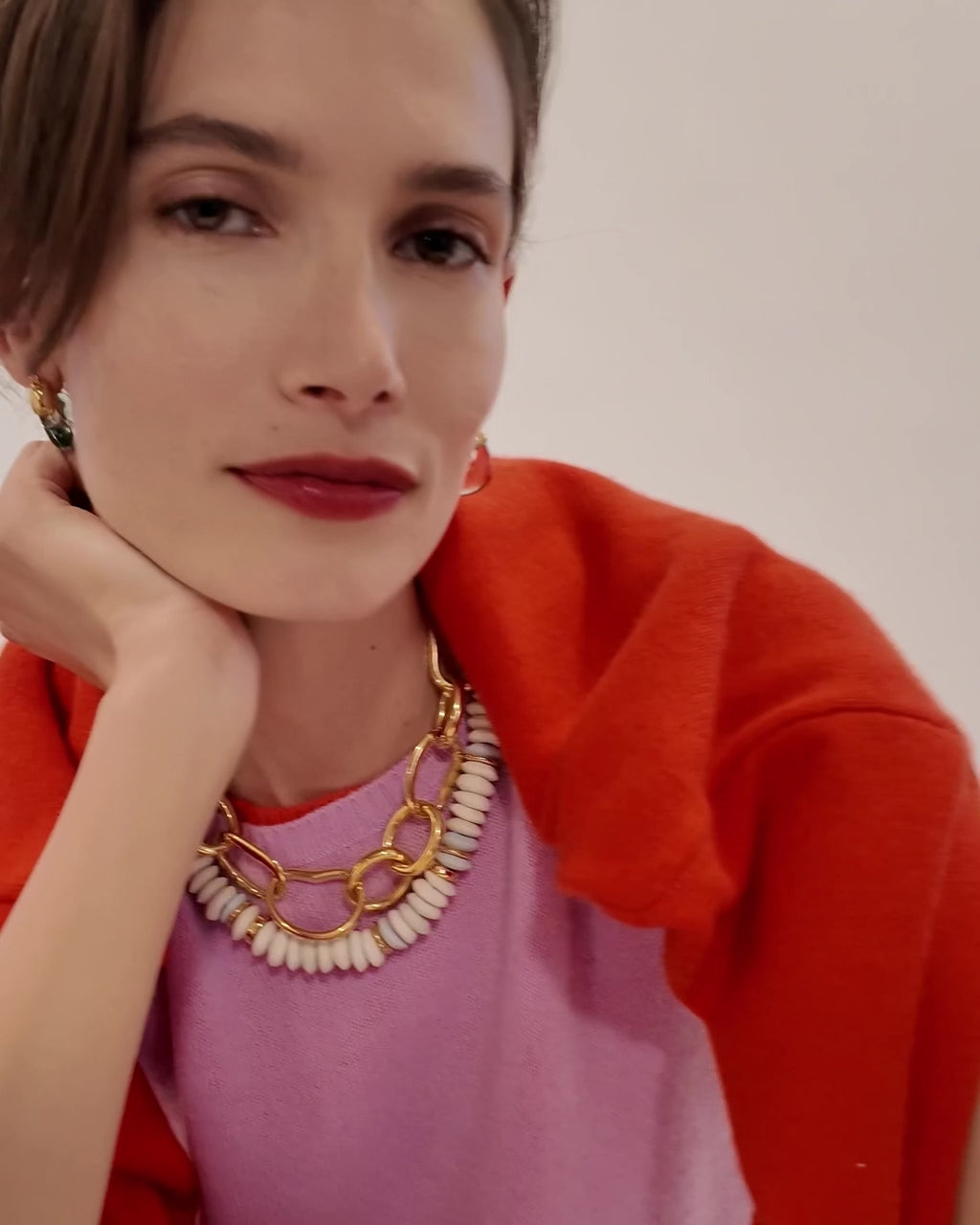 Model in pink and red sweaters wears Laguna Necklace in White with Porto Chain