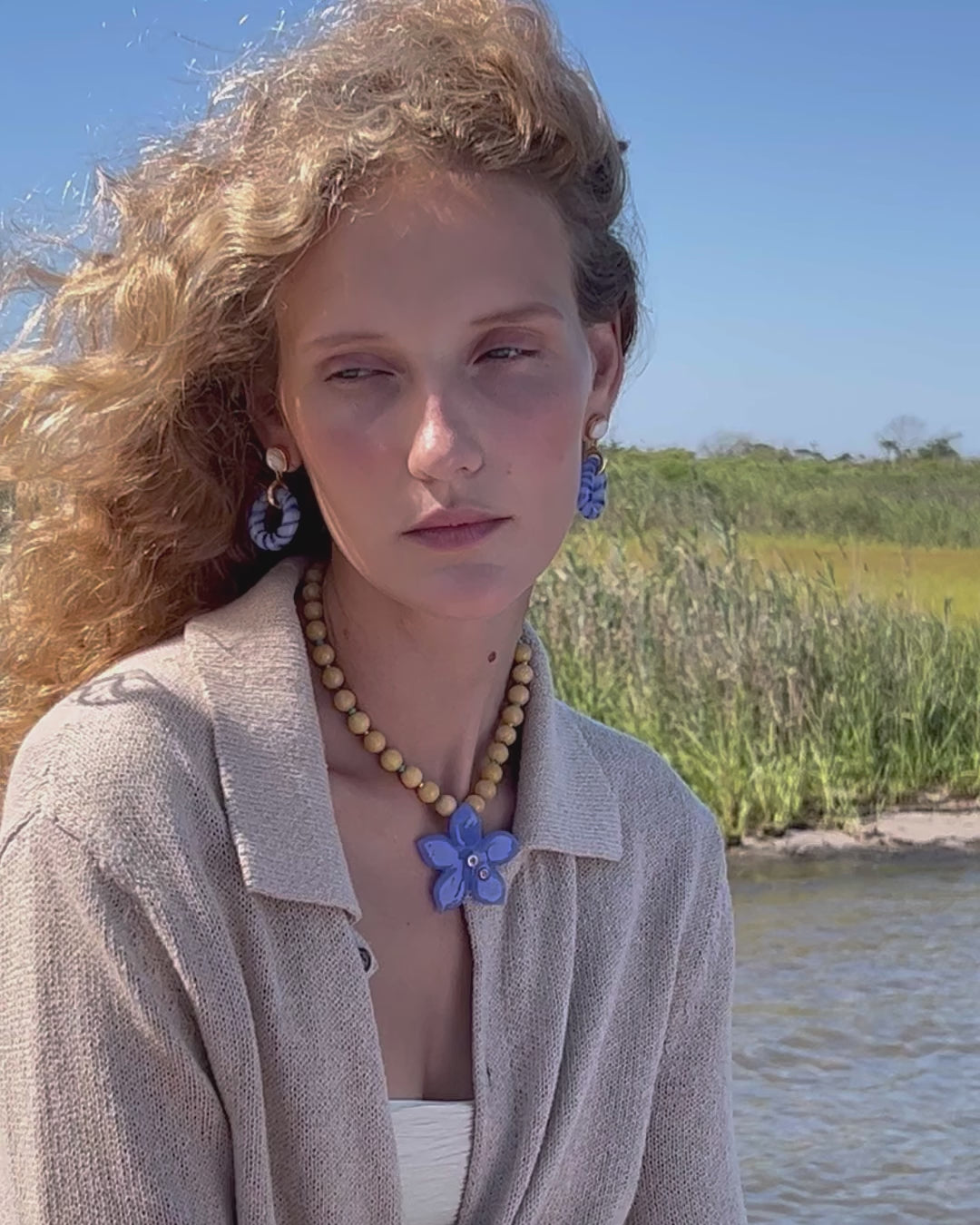 Video of model outdoors in beige sweater with Madeira Glass Earrings and Vinca Flower Necklace.