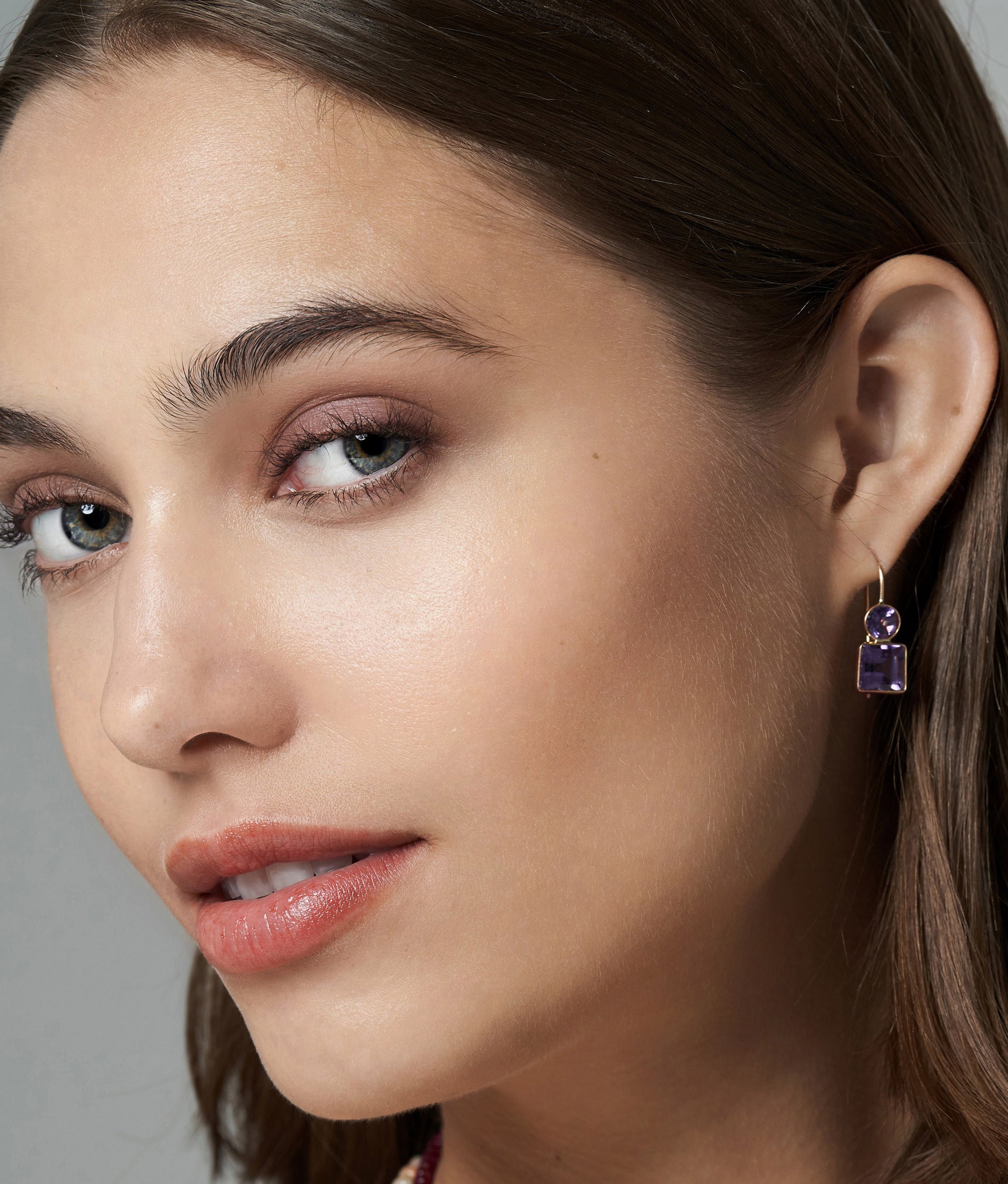 Model in close-up wears the 14k Pastille Earrings in Amethyst.
