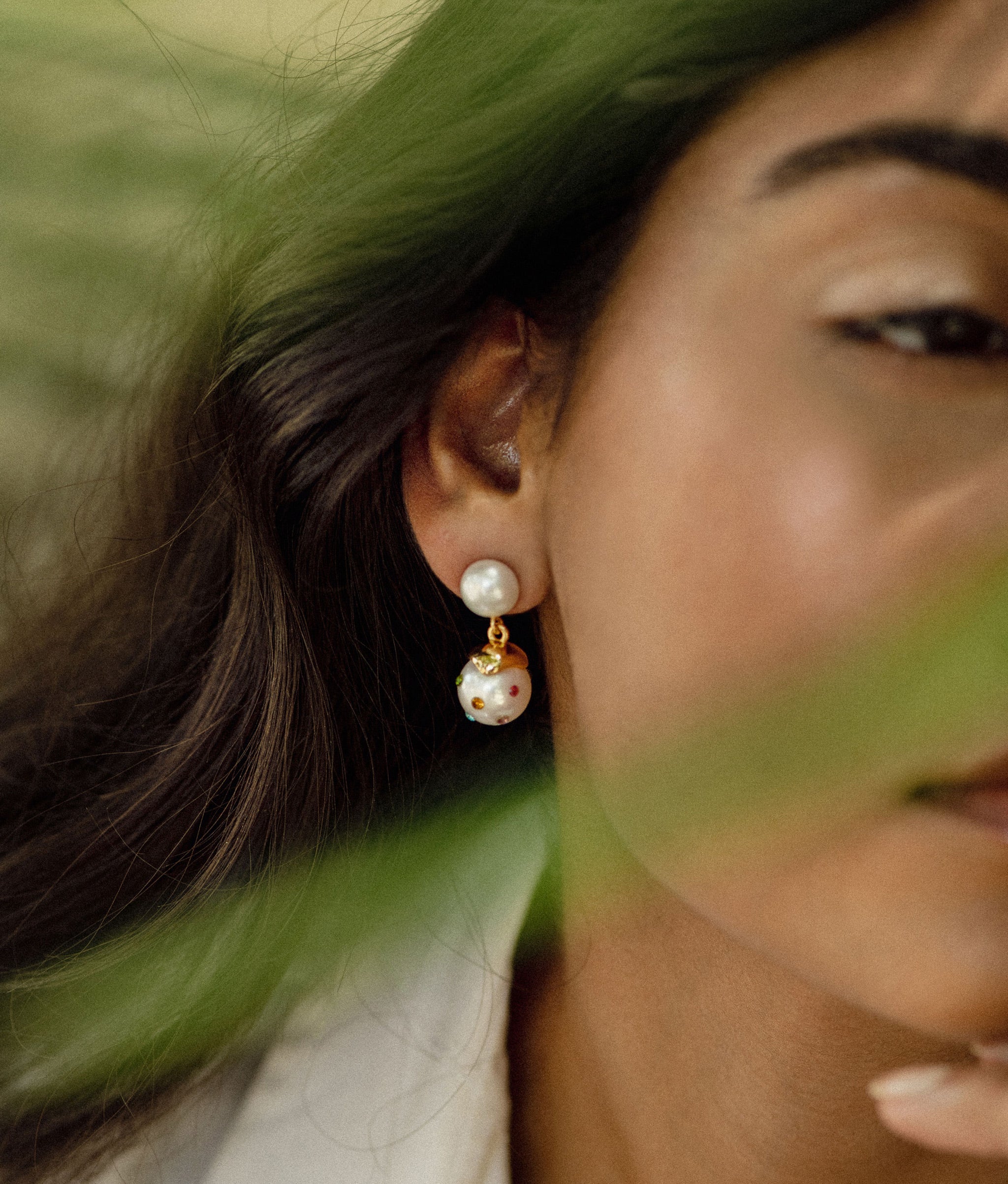 Close up of the confetti drop earrings in white on model.