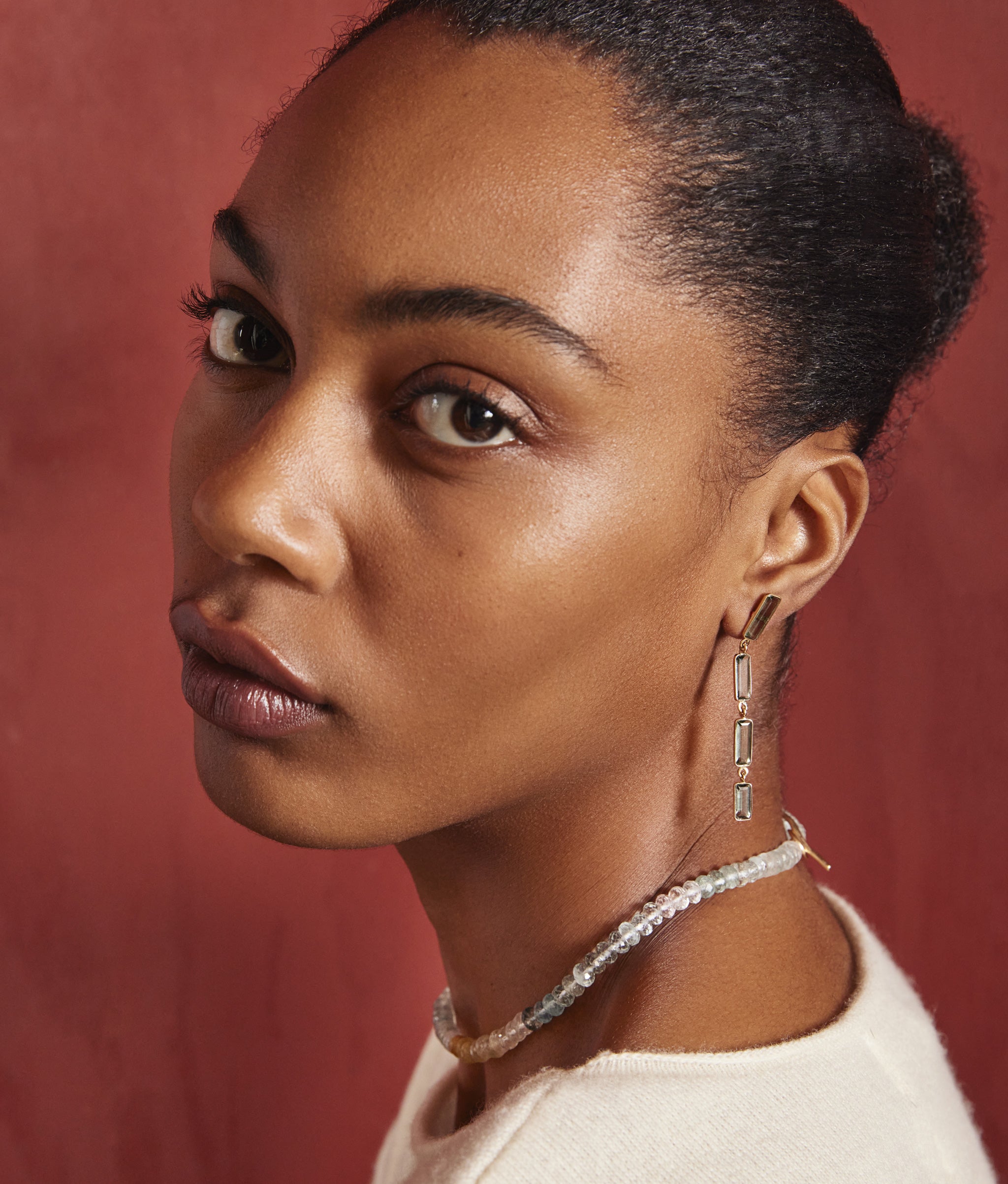 Model in profile on red backdrop wears Rainbow Aquamarine, Morganite & 14k Gold Necklace.
