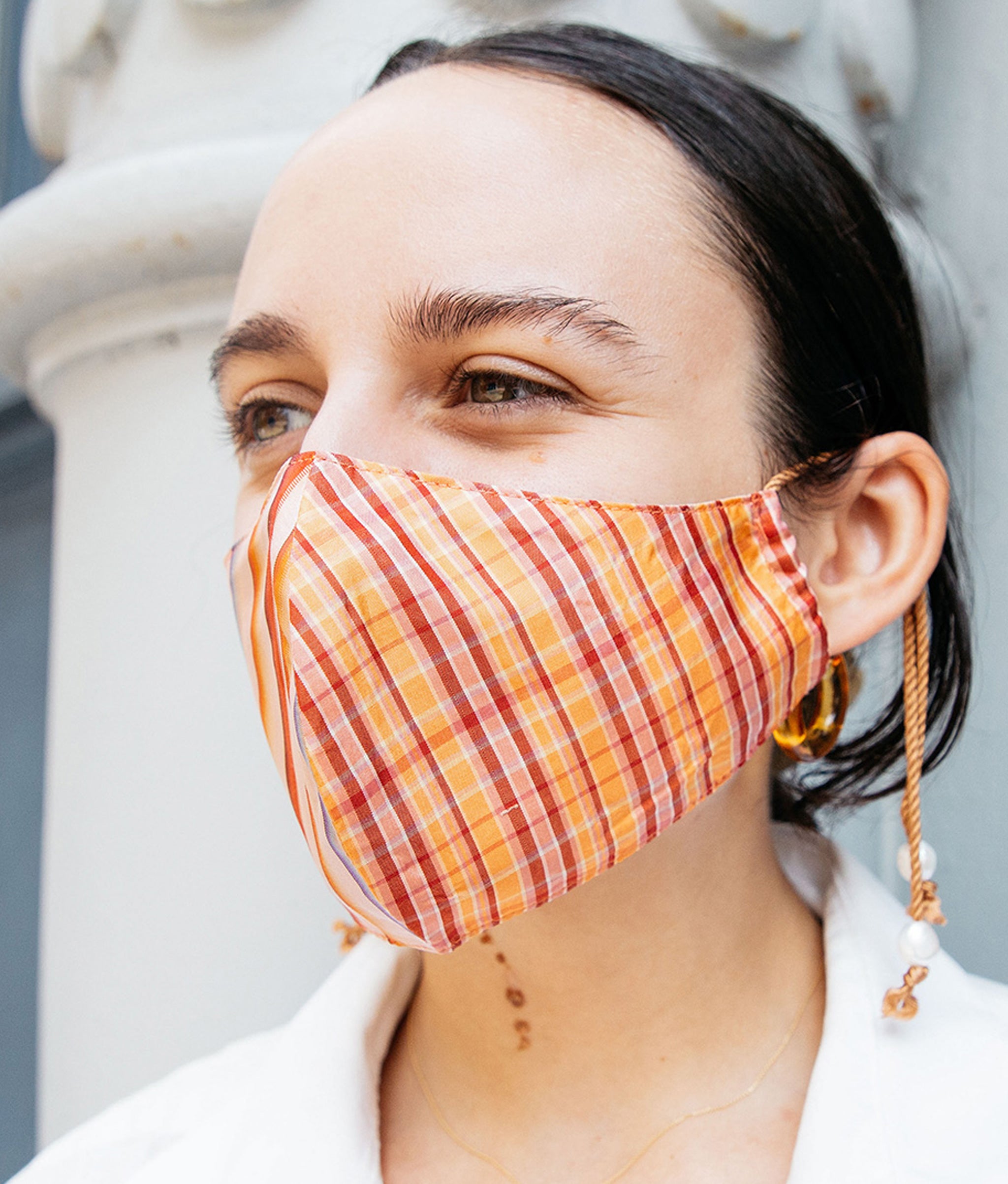Model in close-up in front of building wears Face Mask In Golden Hour.