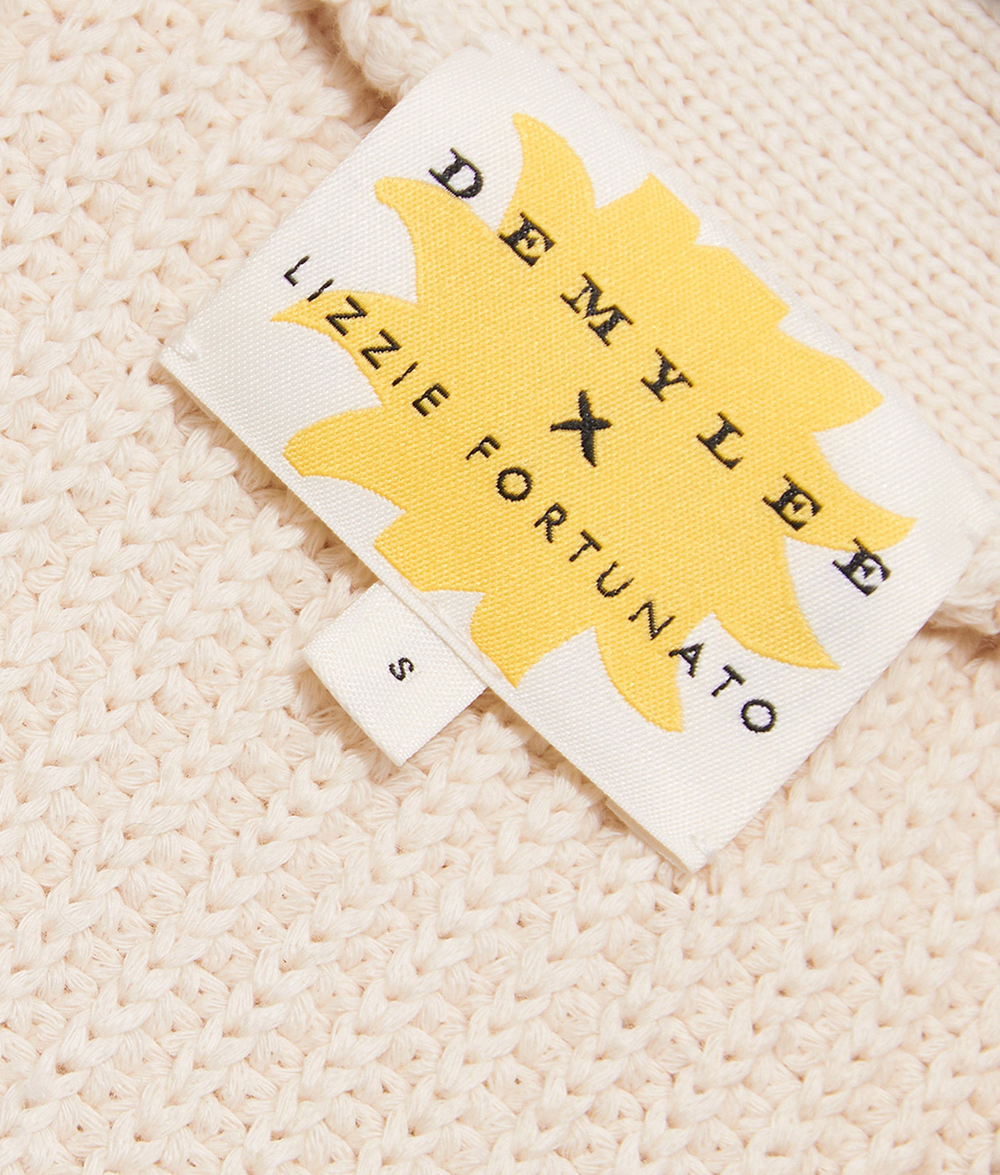 Close-up on knit of Sweet Like Candy Cardigan, with yellow starburst DemyLee x Lizzie Fortunato label.