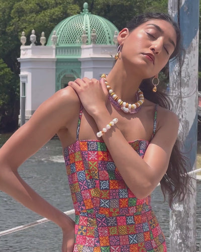 Video of model against water background with sunlight and calypso necklace and grove earrings.
